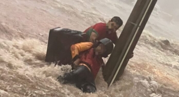Carmo do Paranaíba - Pessoas se seguram em poste para não serem arrastadas pela correnteza durante temporal na cidade