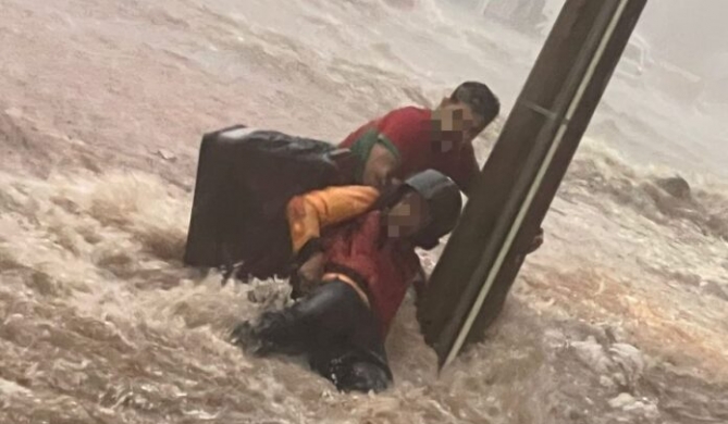Carmo do Paranaíba - Pessoas se seguram em poste para não serem arrastadas pela correnteza durante temporal na cidade